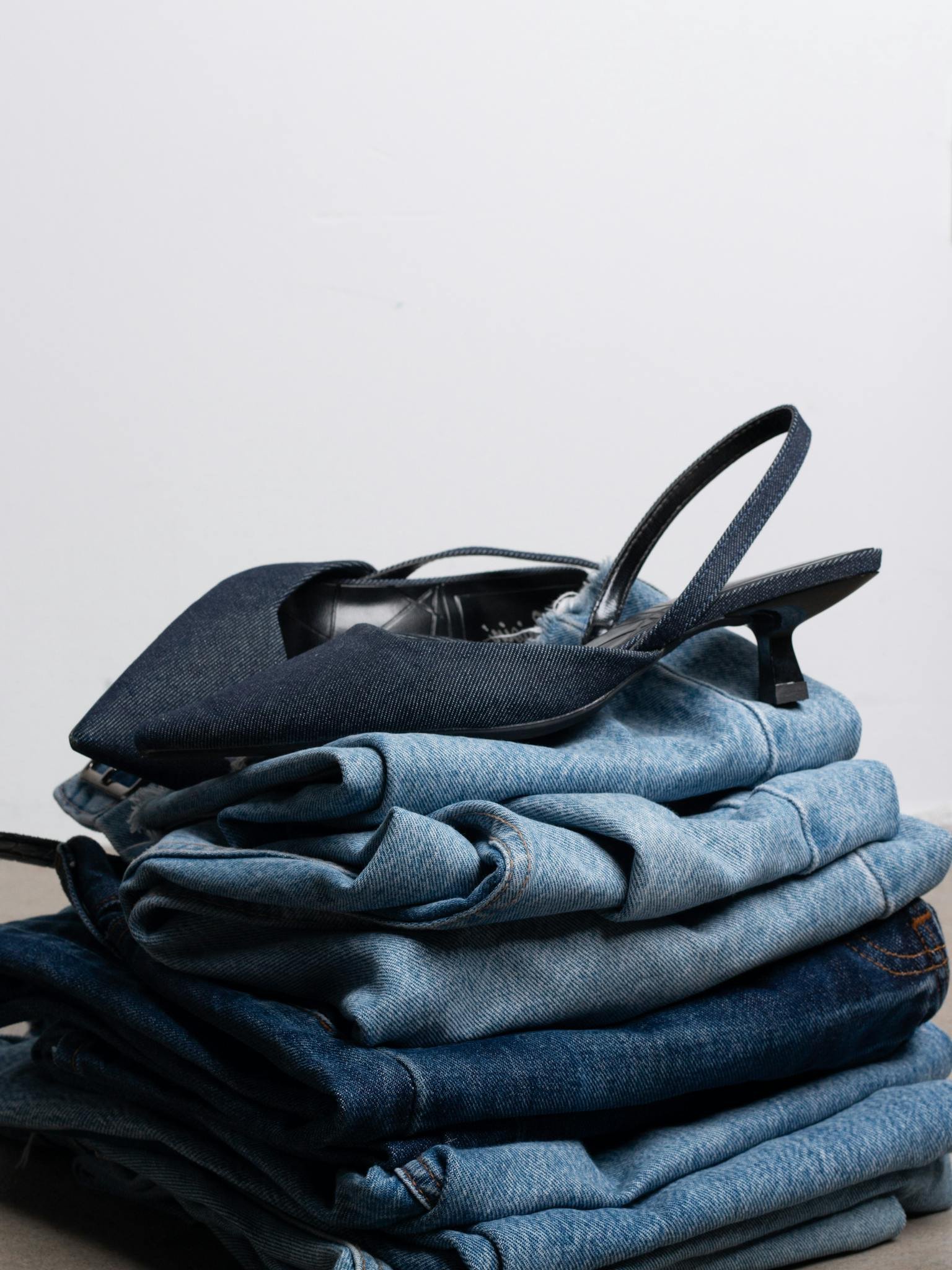 A stylish arrangement of folded jeans topped with sleek black high heels, showcasing modern fashion.